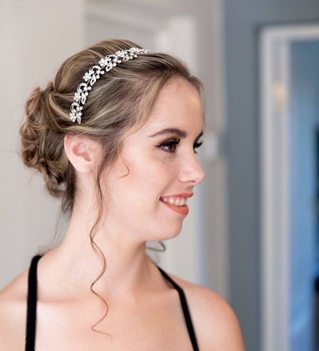 Bride in profile with a loose textured updo, face-framing curls and a crystal headband