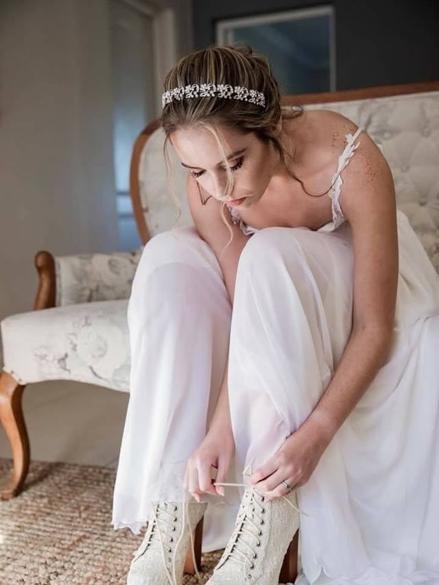 Bride in a jewelled headband lacing up her ankle boots, soft updo with face-framing strands